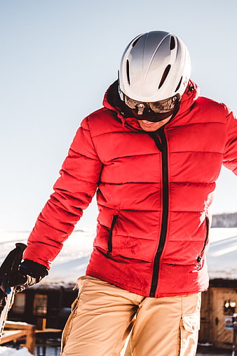 Skier in Red Jacket and White Helmet on Snowy Slope