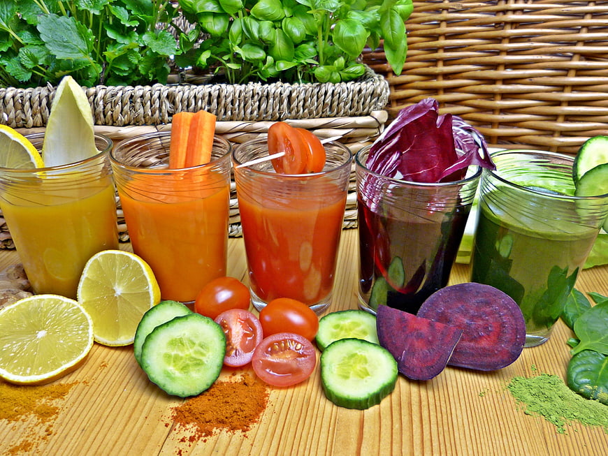 Five colorful fresh vegetable juices with ingredients on wooden table