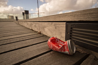Crushed Coca-Cola can on wooden deck