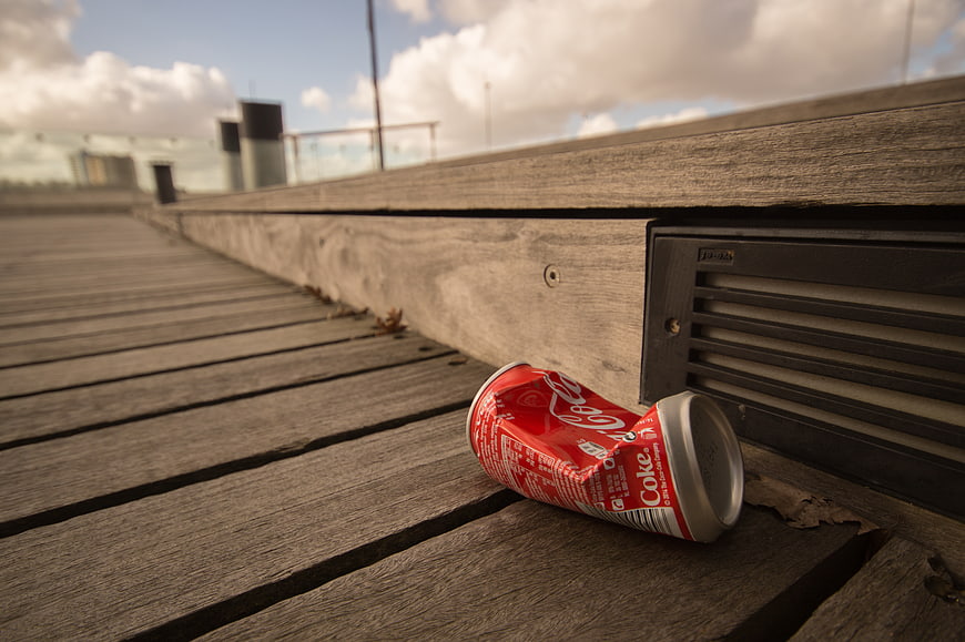 Crushed Coca-Cola can on wooden deck