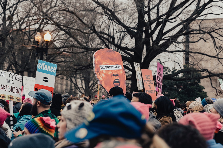 Protest Crowd Holding Signs and Trump Cutout