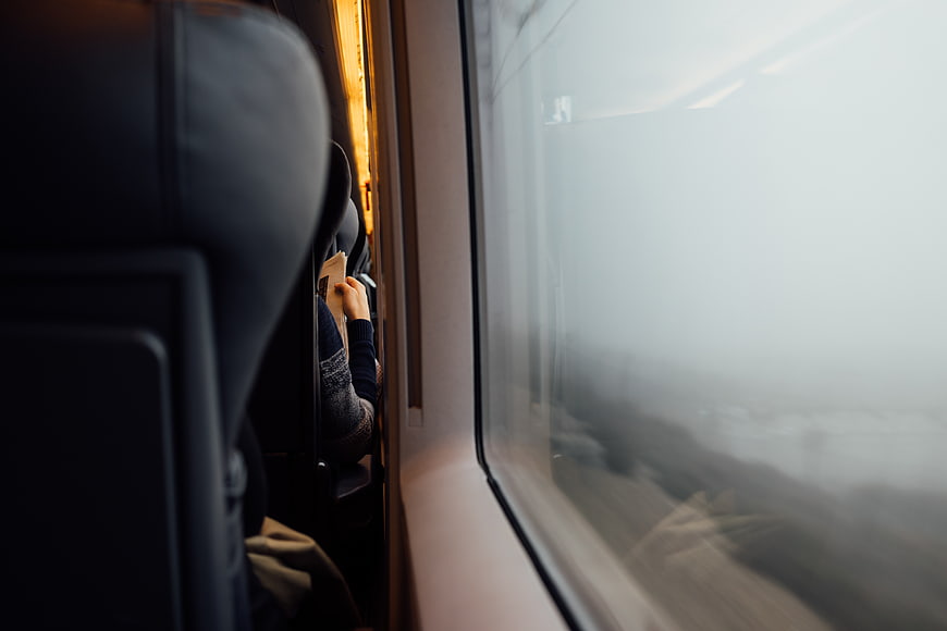 Passenger reading book on train window seat