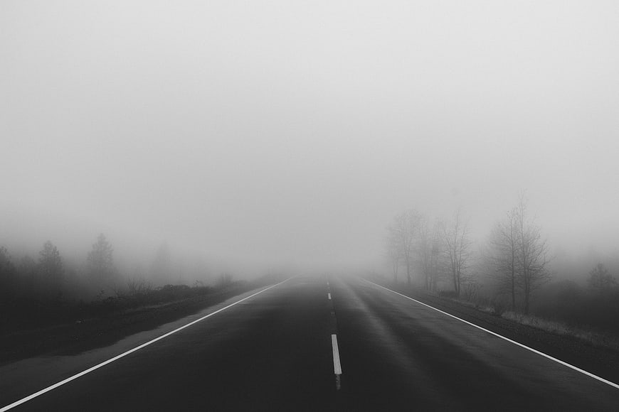 Foggy black and white road disappearing into mist