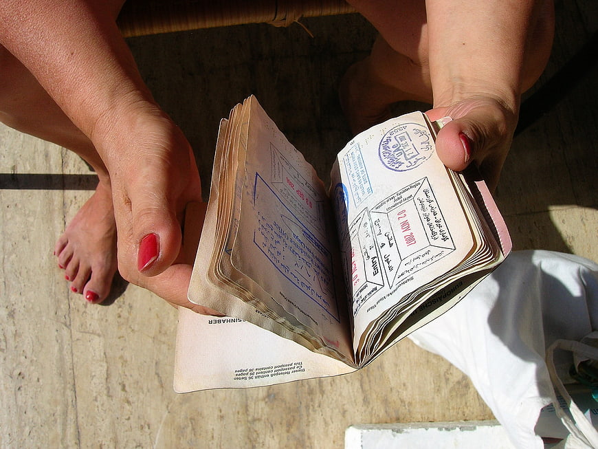 Woman holding open passport with visa stamps