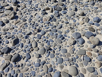 Gray pebbles and stones on sandy beach texture