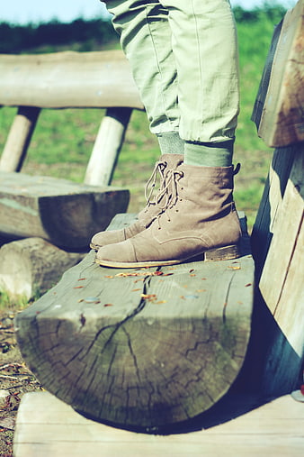 Vintage brown boots on rustic wooden log outdoors