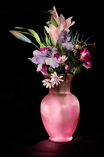 Pink frosted vase with colorful artificial flowers on black background
