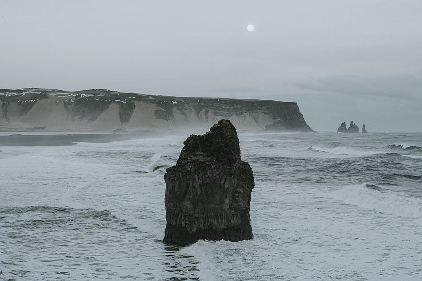 Dramatic coastal landscape with sea stack and cliffs under moonlight