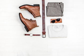 Men's fashion flat lay with brown boots, belt, and gray trousers