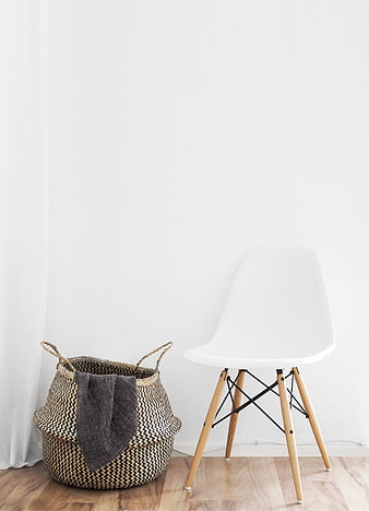 Minimalist white chair and woven basket on wooden floor