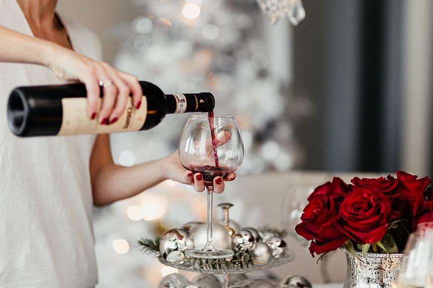 Woman Pouring Red Wine with Christmas Decorations