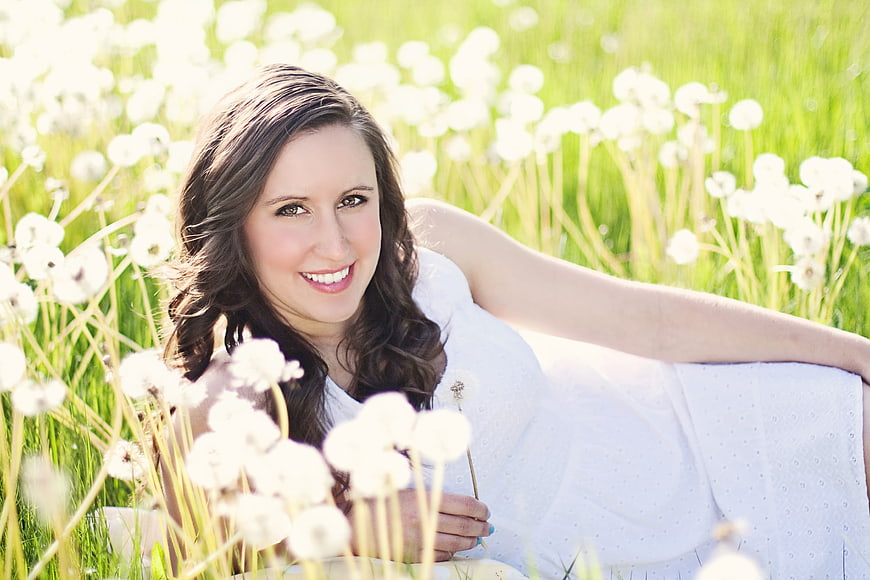 Happy woman lying in a sunny field of dandelions