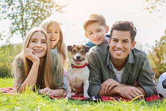 Happy family with dog relaxing on picnic blanket in park