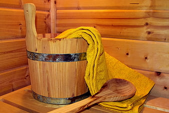 Wooden sauna bucket with yellow towel and ladle