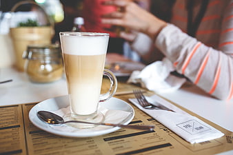 Latte in Tall Glass on Cafe Table with Menu