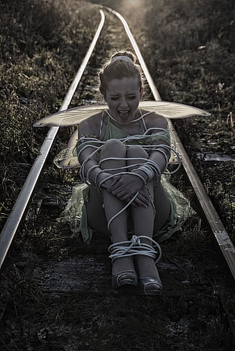 Distressed fairy tied to railroad tracks screaming in despair
