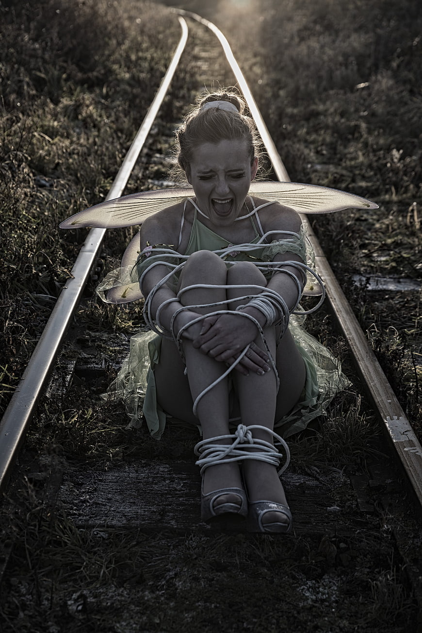 Distressed fairy tied to railroad tracks screaming in despair