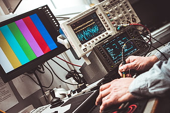 Engineer Testing Electronics with Oscilloscope and Multimeter