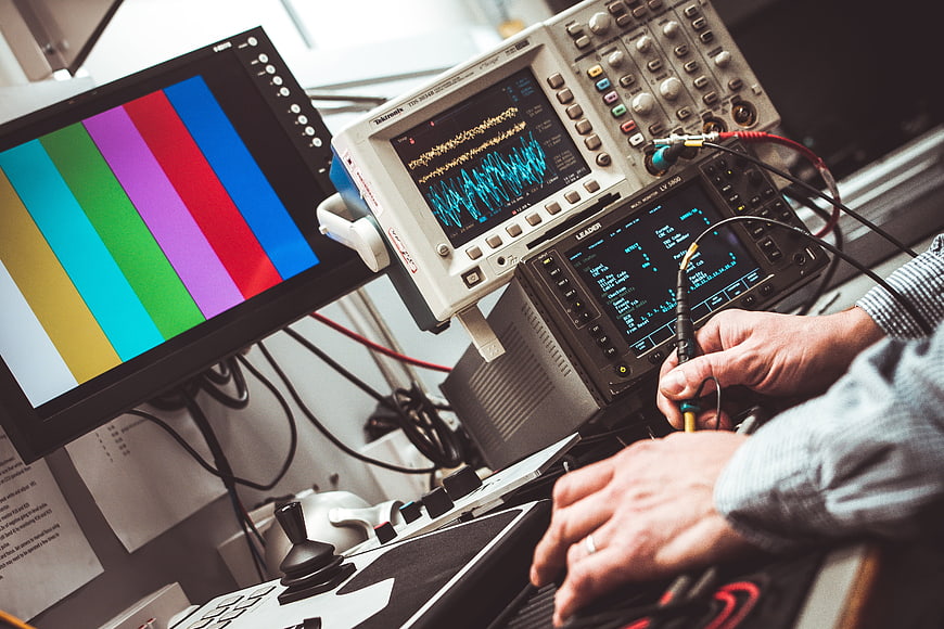 Engineer Testing Electronics with Oscilloscope and Multimeter