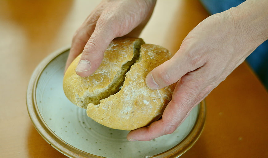 Hands Breaking Fresh Artisan Bread Over Ceramic Plate