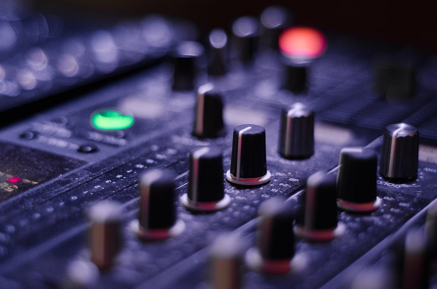 Close-up of audio mixer knobs with glowing green and red lights
