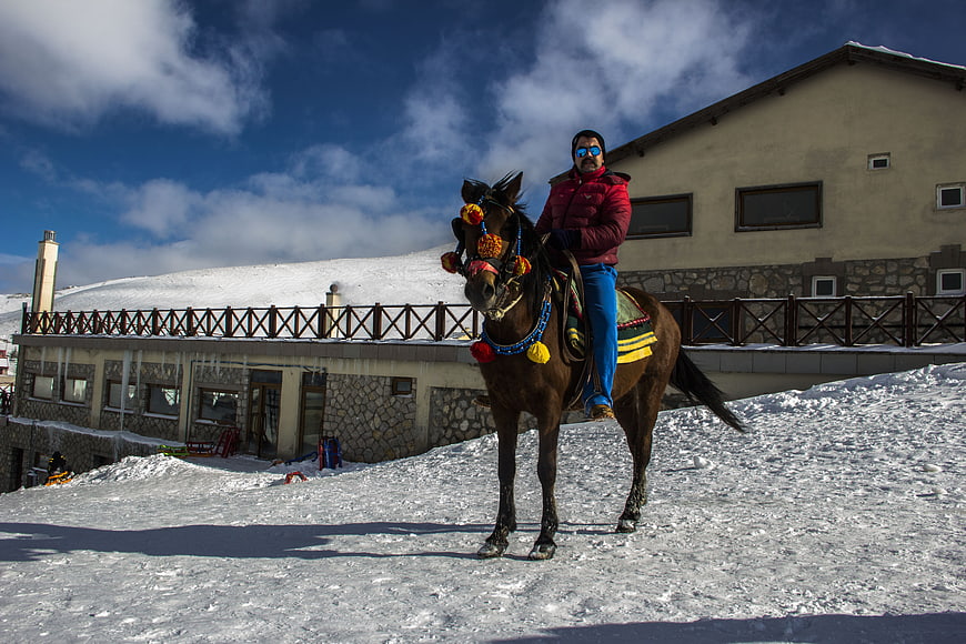 Man Riding Decorated Horse in Snowy Mountain Village
