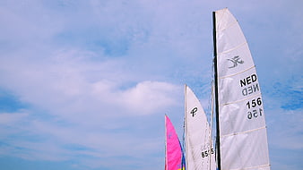 Sailboat sails against blue sky with clouds