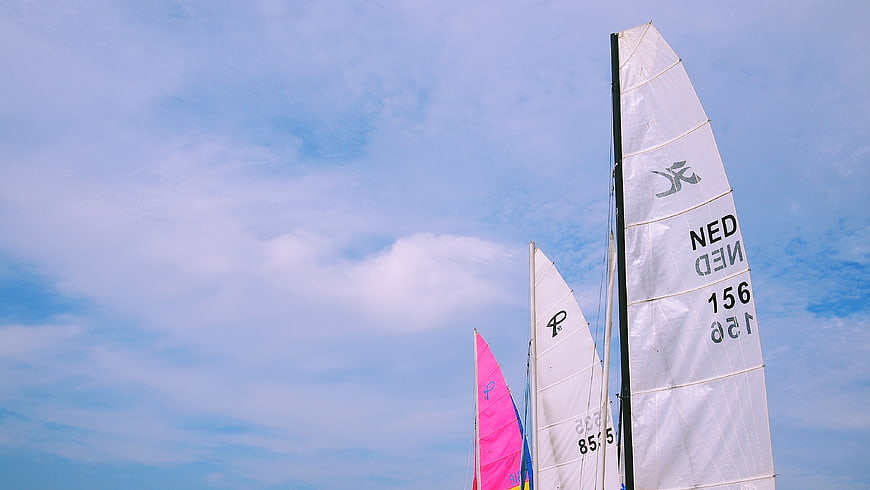 Sailboat sails against blue sky with clouds