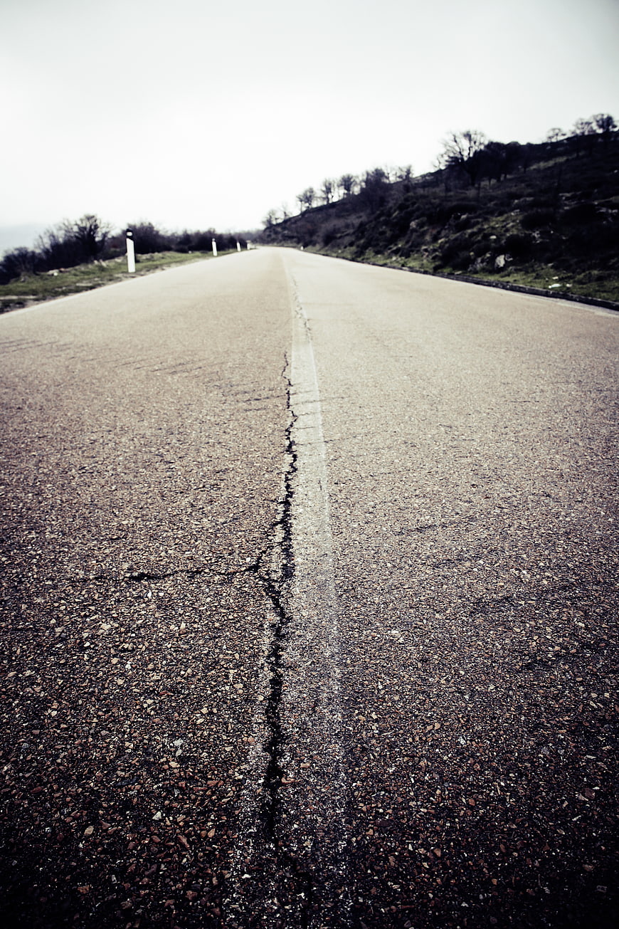 Low angle view of cracked asphalt road stretching into distance