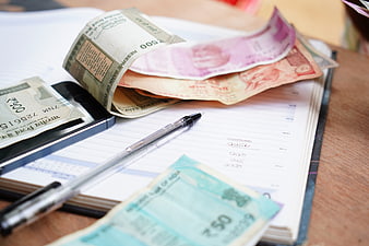 Indian Rupee Banknotes, Smartphone, and Ledger on Wooden Desk