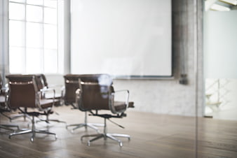 Blurred modern office conference room with brown leather chairs and whiteboard