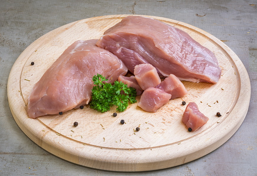 Raw Pork Fillet And Chops On Wooden Cutting Board With Parsley