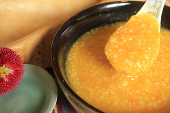 Close-up of orange millet porridge in a black ceramic bowl
