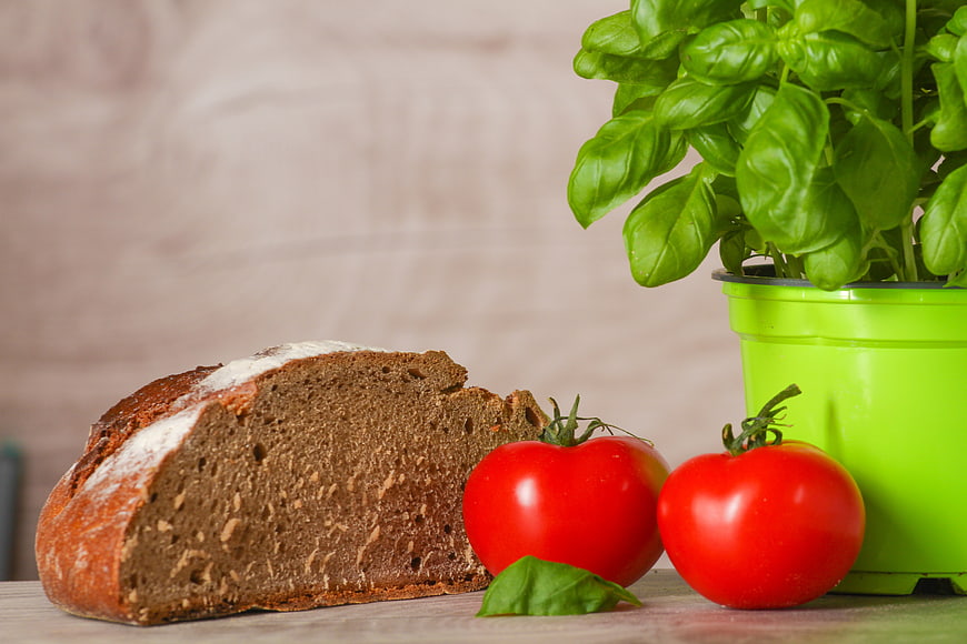 Fresh Whole Wheat Bread, Tomatoes, and Basil on Wooden Table
