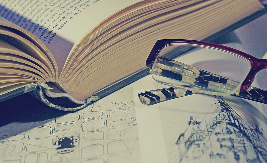 Open book with glasses and architectural sketches