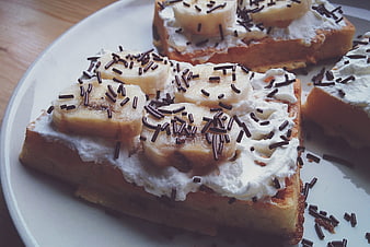 Close-up of waffles with banana, cream, and chocolate sprinkles