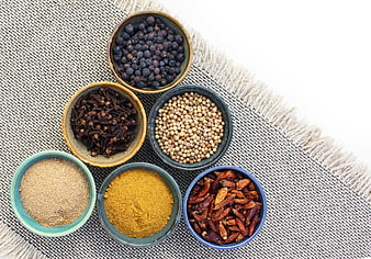 Top View of Spices in Ceramic Bowls on Textured Fabric