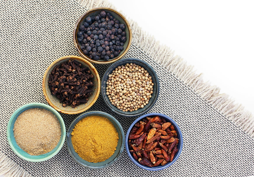 Top View of Spices in Ceramic Bowls on Textured Fabric