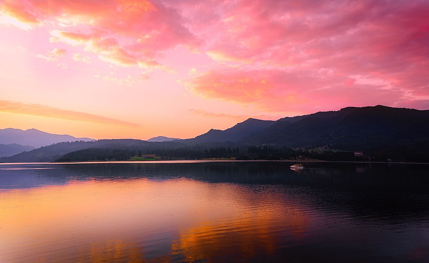 Vibrant Pink Sunset Over Calm Lake with Mountain Silhouettes