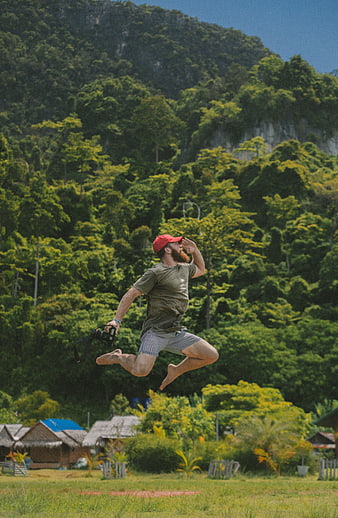 Man jumping with camera in tropical rural landscape