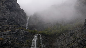 Misty waterfall cascading down rocky mountain cliffs