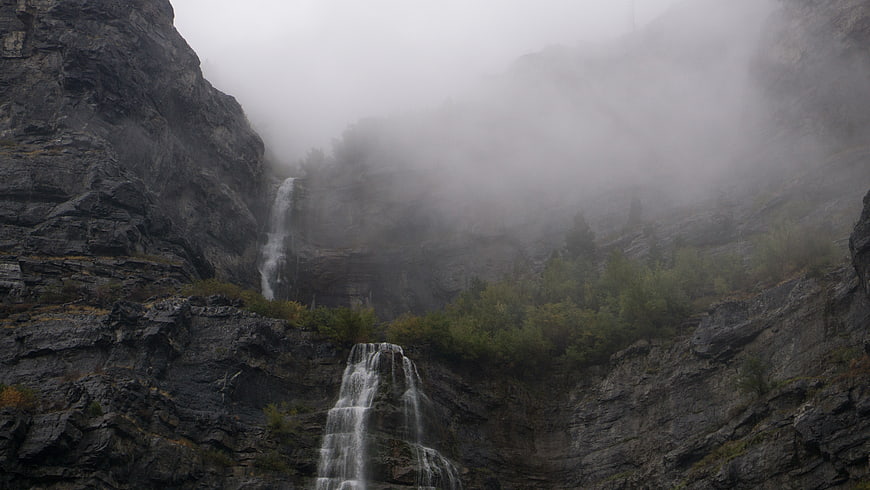 Misty waterfall cascading down rocky mountain cliffs