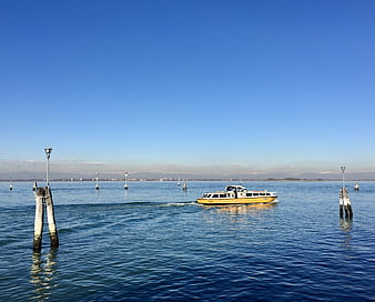 Yellow water taxi boat cruising on calm blue Venetian lagoon