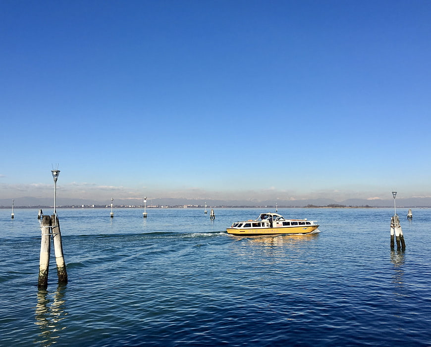 Yellow water taxi boat cruising on calm blue Venetian lagoon