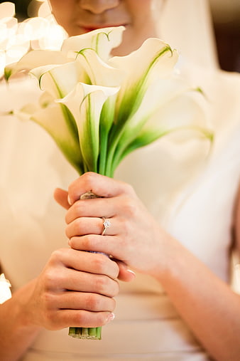 Bride holding white calla lily bouquet with engagement ring
