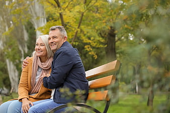 Happy Senior Couple Sitting on Park Bench in Autumn