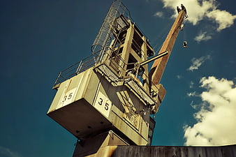 Low angle view of industrial crane against blue sky