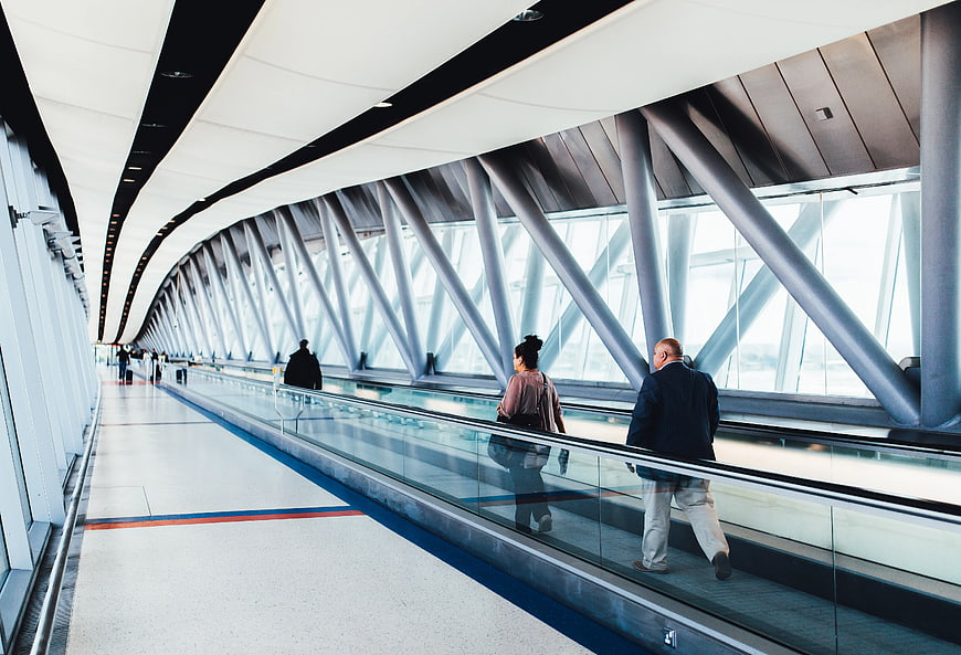 Travelers on Airport Moving Walkway with Modern Architecture