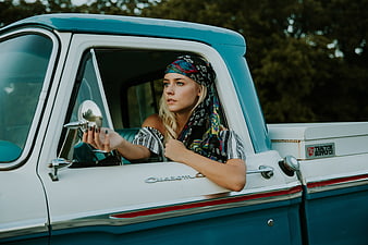 Blonde woman in vintage truck with colorful headscarf