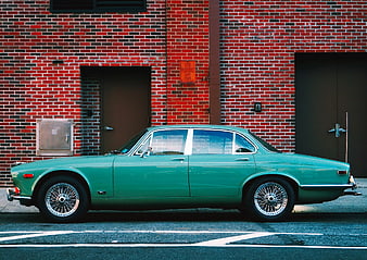 Vintage Green Classic Car Parked Against Red Brick Wall